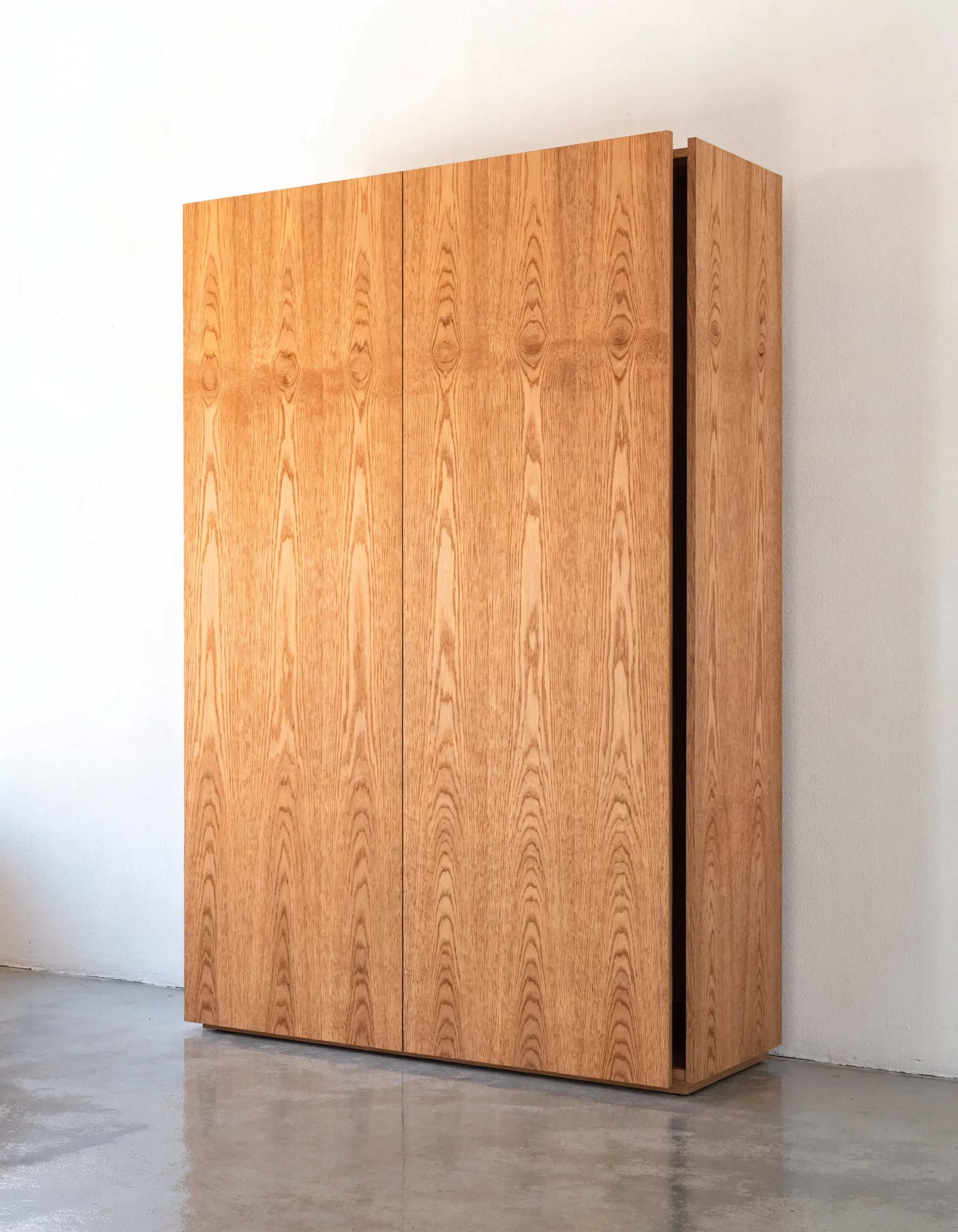 Freistehender Einbauschrank aus Eiche vor einer weissen Wand.